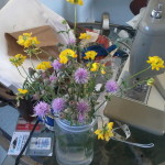 Thistle and vetch flowers in vase on sewing table
