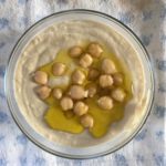 hummus in a bowl garnished with whole beans and olive oil